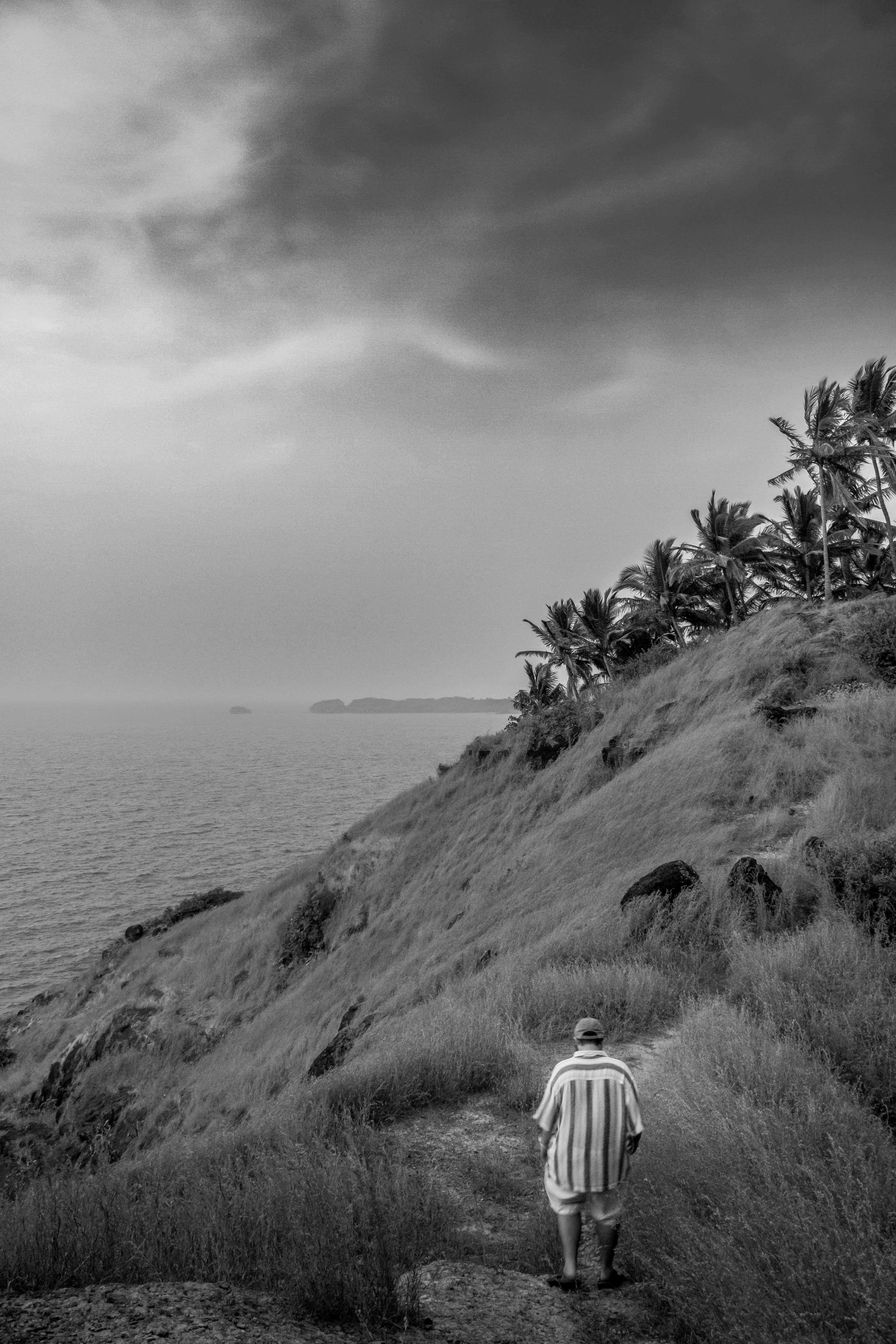 Black-and-white photograph of a lone figure on a misty coastal cliff